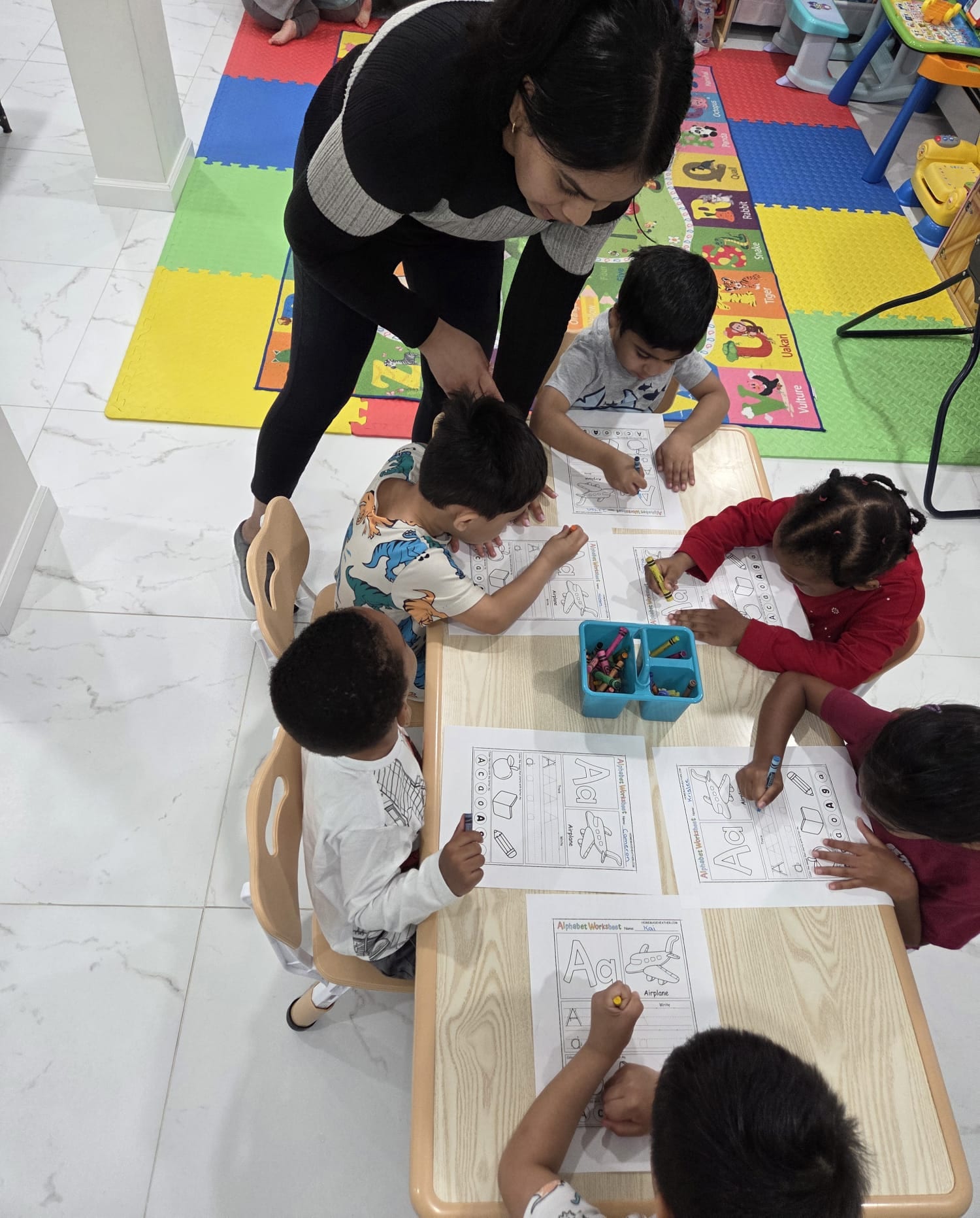 Children learning at a table with alphabet worksheets