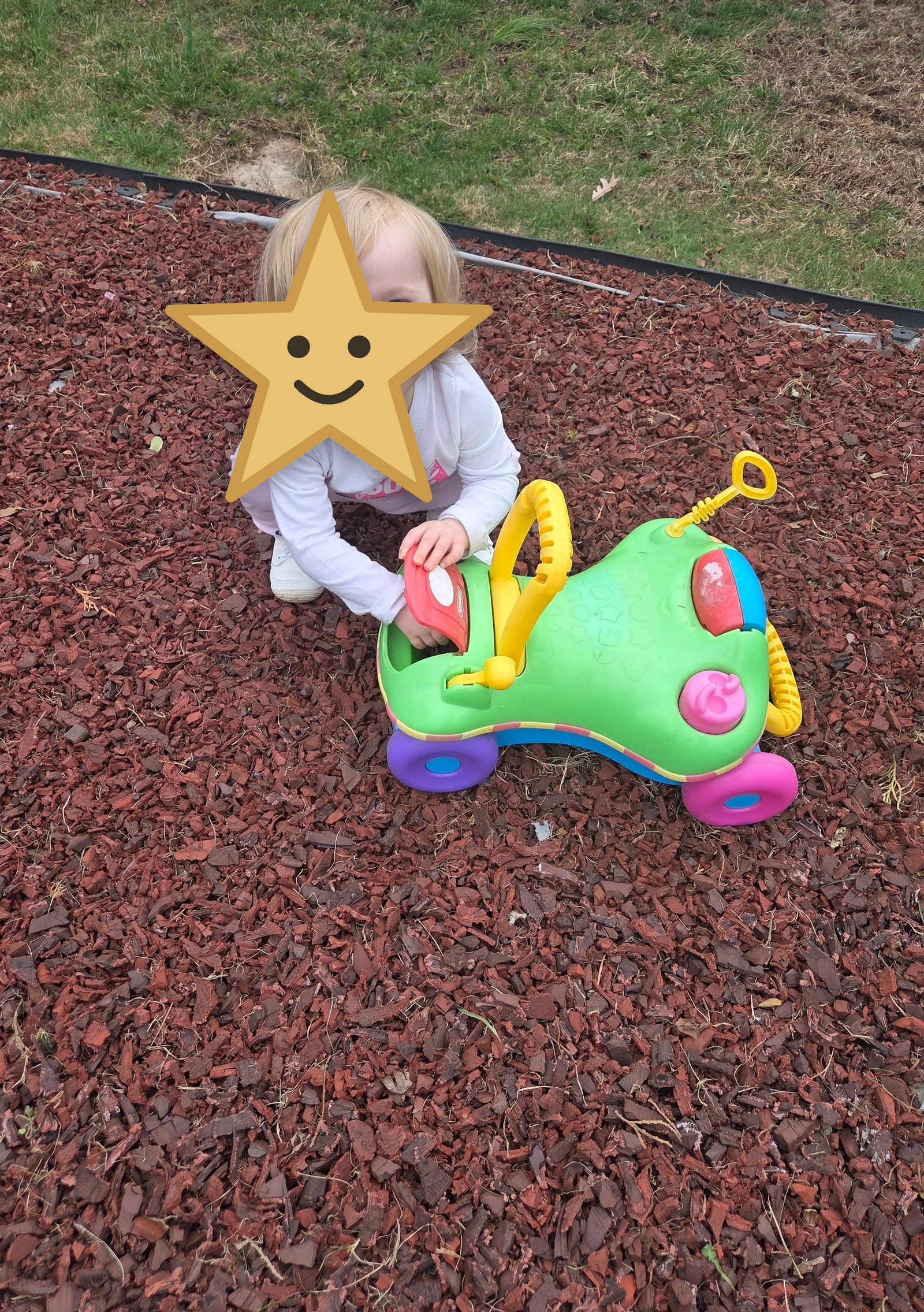 Toddler laughing while playing with a ride-on car